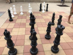 large black chess pieces on chessboard on ground